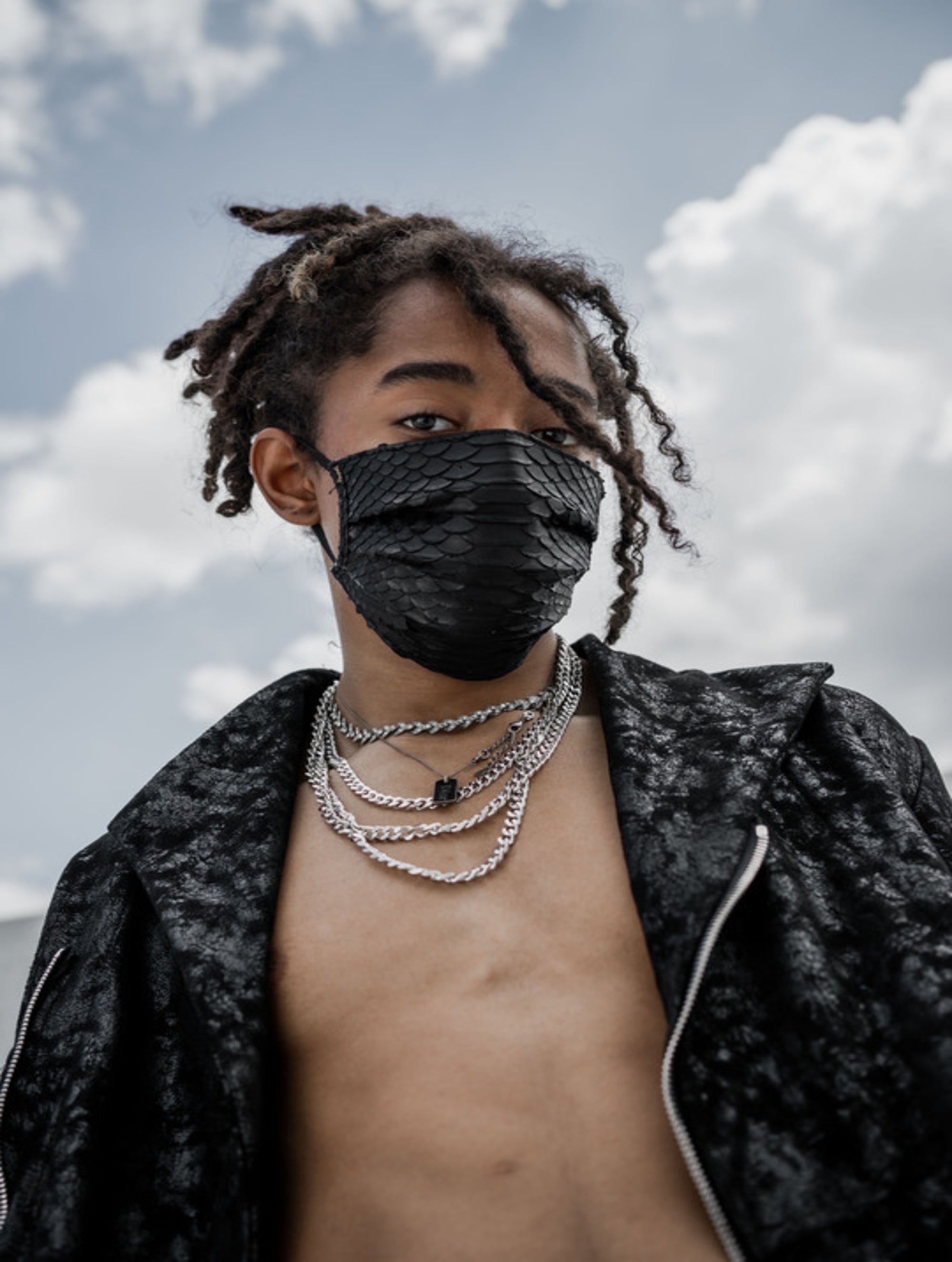 A man wearing black disposable python leather face mask, chain silver necklace, and designer black jacket outfit ideas