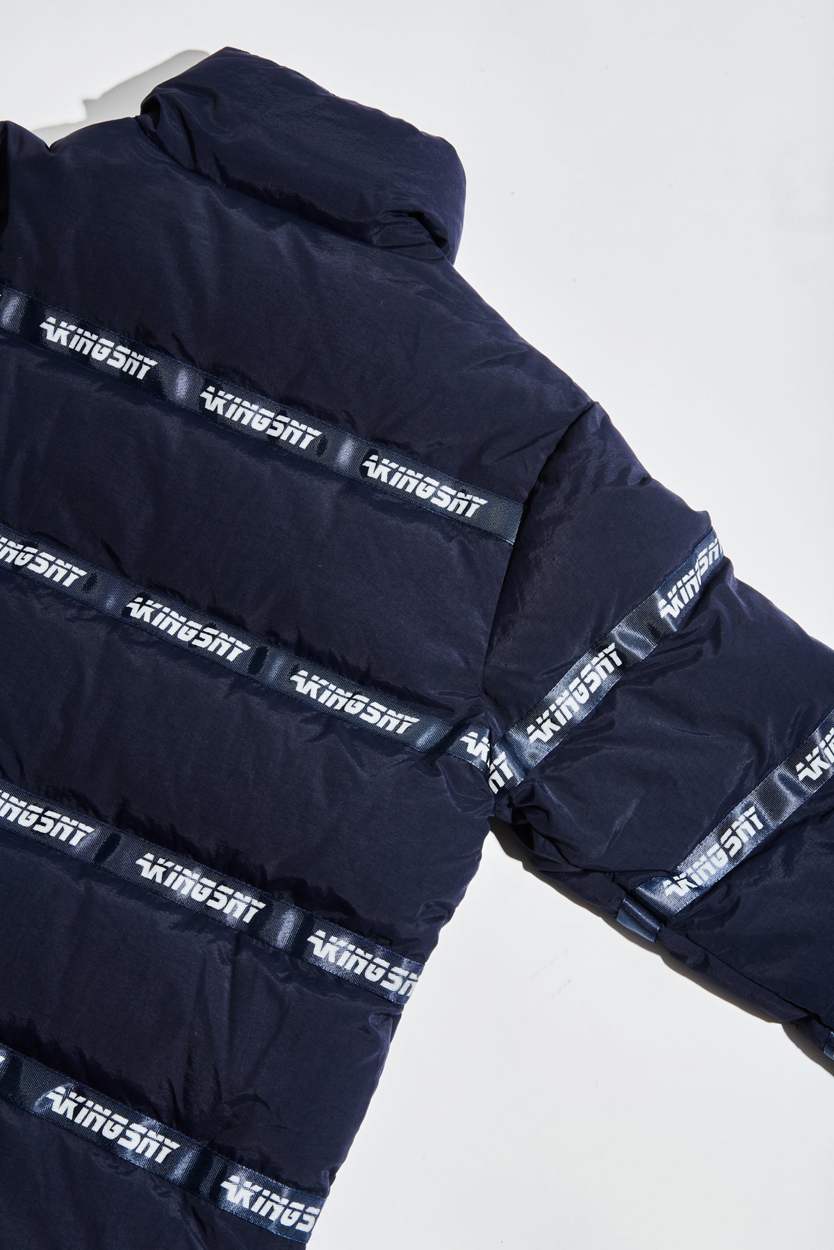 BACK VIEW OF LOGO PUFFER JACKET NAVY - AKINGS SHOWING INSEAM AND LOGO PATCH